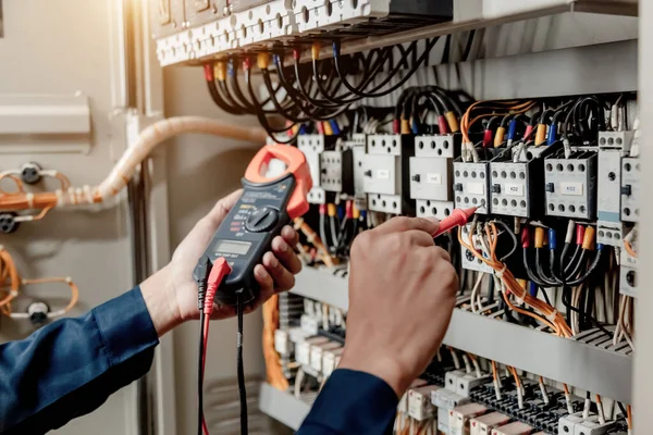 Elektrik mühendisi elektrik sistemi kontrol dolabındaki elektrik akımını ve elektrik hattını test etmek için çoklu metre kullanıyor..