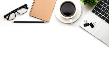 Üst kattaki ofis masasında yatıyordu. Çalışma alanı boş, ofis malzemeleri, kalem, yeşil yaprak ve beyaz arka planda kahve fincanı. .