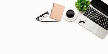 Üst kattaki ofis masasında yatıyordu. Çalışma alanı boş, ofis malzemeleri, kalem, yeşil yaprak ve beyaz arka planda kahve fincanı. .