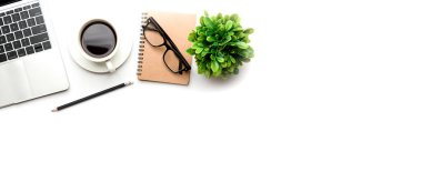 Üst kattaki ofis masasında yatıyordu. Çalışma alanı boş, ofis malzemeleri, kalem, yeşil yaprak ve beyaz arka planda kahve fincanı. .