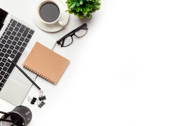 Üst kattaki ofis masasında yatıyordu. Çalışma alanı boş, ofis malzemeleri, kalem, yeşil yaprak ve beyaz arka planda kahve fincanı. .