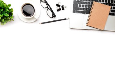 Üst kattaki ofis masasında yatıyordu. Çalışma alanı boş, ofis malzemeleri, kalem, yeşil yaprak ve beyaz arka planda kahve fincanı. .