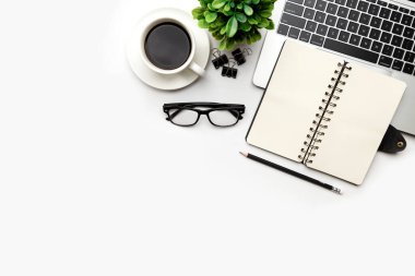 Üst kattaki ofis masasında yatıyordu. Çalışma alanı boş, ofis malzemeleri, kalem, yeşil yaprak ve beyaz arka planda kahve fincanı. .