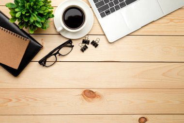 Üst kattaki ofis masasında yatıyordu. Çalışma alanı boş, ofis malzemeleri, kalem, yeşil yaprak ve beyaz arka planda kahve fincanı. .