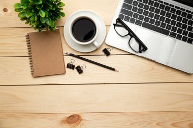 Üst kattaki ofis masasında yatıyordu. Çalışma alanı boş, ofis malzemeleri, kalem, yeşil yaprak ve beyaz arka planda kahve fincanı. .