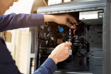 Bilgisayarları tamir etmek için tornavidayla çalışan bir teknisyen.;