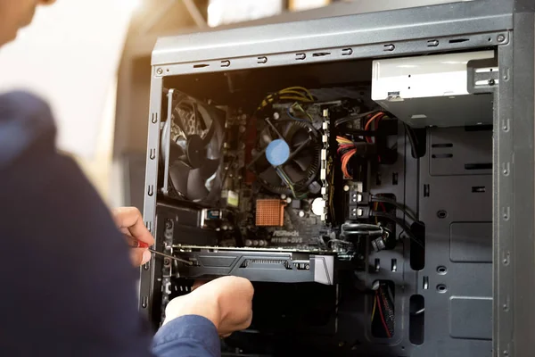 Bilgisayarları tamir etmek için tornavidayla çalışan bir teknisyen.;