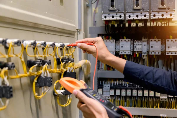 電気技師は 電気キャビネット制御における電力線の電圧と電流を測定する試験機を動作させます — ストック写真