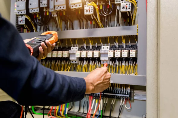 電気技師は 電気キャビネット制御における電力線の電圧と電流を測定する試験機を動作させます — ストック写真