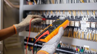 Elektrik mühendisi elektrik sistemi kontrol dolabındaki elektrik akımını ve elektrik hattını test etmek için çoklu metre kullanıyor..