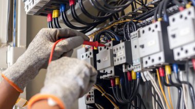 Elektrik mühendisi elektrik sistemi kontrol dolabındaki elektrik akımını ve elektrik hattını test etmek için çoklu metre kullanıyor..