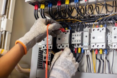 Elektrik mühendisi elektrik sistemi kontrol dolabındaki elektrik akımını ve elektrik hattını test etmek için çoklu metre kullanıyor..