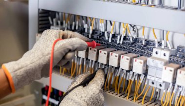 Elektrik mühendisi elektrik sistemi kontrol dolabındaki elektrik akımını ve elektrik hattını test etmek için çoklu metre kullanıyor..