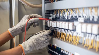 Elektrik mühendisi elektrik sistemi kontrol dolabındaki elektrik akımını ve elektrik hattını test etmek için çoklu metre kullanıyor..