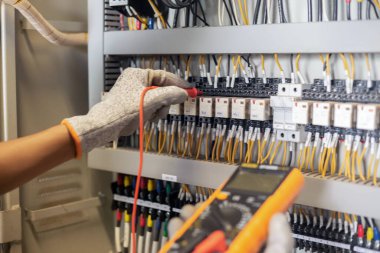 Elektrik mühendisi elektrik sistemi kontrol dolabındaki elektrik akımını ve elektrik hattını test etmek için çoklu metre kullanıyor..