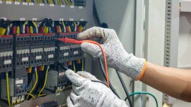 Elektrik mühendisi elektrik sistemi kontrol dolabındaki elektrik akımını ve elektrik hattını test etmek için çoklu metre kullanıyor..