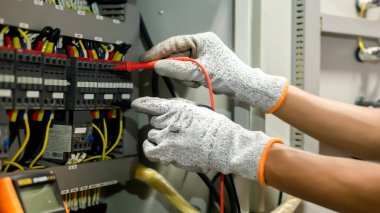 Elektrik mühendisi elektrik sistemi kontrol dolabındaki elektrik akımını ve elektrik hattını test etmek için çoklu metre kullanıyor..