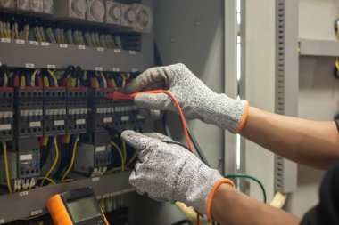 Elektrik mühendisi elektrik sistemi kontrol dolabındaki elektrik akımını ve elektrik hattını test etmek için çoklu metre kullanıyor..