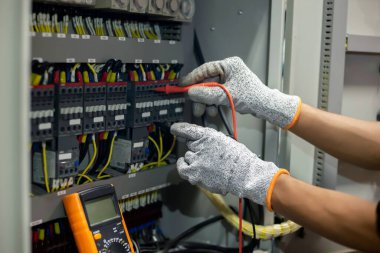 Elektrik mühendisi elektrik sistemi kontrol dolabındaki elektrik akımını ve elektrik hattını test etmek için çoklu metre kullanıyor..