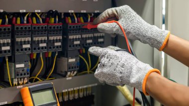 Elektrik mühendisi elektrik sistemi kontrol dolabındaki elektrik akımını ve elektrik hattını test etmek için çoklu metre kullanıyor..