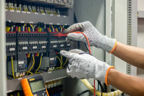 Elektrik mühendisi elektrik sistemi kontrol dolabındaki elektrik akımını ve elektrik hattını test etmek için çoklu metre kullanıyor..