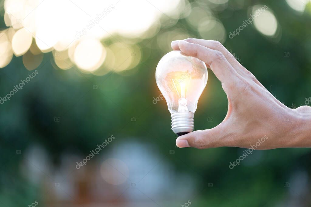 Hand holding light bulb, energy sources for renewable, natural energy concept.