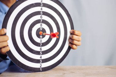 Hedef iş merkezi iş hedefi kavramını hedef alan bir dart tutan işadamı - iş hedefleme, nişan alma, odaklanma konsepti, pazarlamayı hedeflemek için metafor veya ticari başarı için hedef ok.