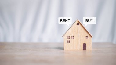 Buy or Rent 'le çalışan iş adamı, kopyalama alanı. Mülk yatırımı ve ev kredisi finansal konsepti El 'in ahşap eve para yığını koyması..