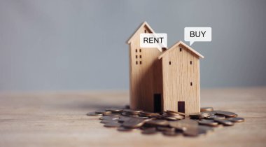 Buy or Rent 'le çalışan iş adamı, kopyalama alanı. Mülk yatırımı ve ev kredisi finansal konsepti El 'in ahşap eve para yığını koyması..