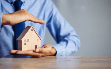 Sigorta evi ve aile sağlığı konsepti. Sigorta acentesi kapsamayı sembolize eden el koruma modelini sunar..