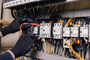 Elektrik mühendisi, elektrik kabinesi kontrolündeki voltaj ve elektrik akımını ölçen bir testçi ve röle koruma sistemindeki kabloları kontrol ediyor. Körfez kontrol birimi. Orta gerilim şalteri.