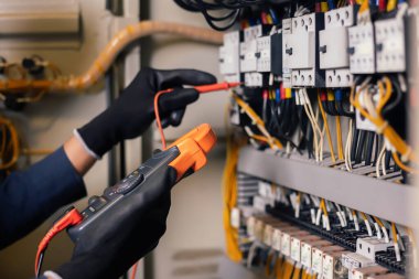 Elektrik mühendisi, elektrik kabinesi kontrolündeki voltaj ve elektrik akımını ölçen bir testçi ve röle koruma sistemindeki kabloları kontrol ediyor. Körfez kontrol birimi. Orta gerilim şalteri.