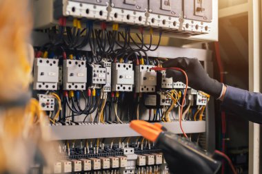 Elektrik mühendisi, elektrik kabinesi kontrolündeki voltaj ve elektrik akımını ölçen bir testçi ve röle koruma sistemindeki kabloları kontrol ediyor. Körfez kontrol birimi. Orta gerilim şalteri.