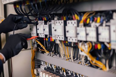 Elektrik mühendisi, elektrik kabinesi kontrolündeki voltaj ve elektrik akımını ölçen bir testçi ve röle koruma sistemindeki kabloları kontrol ediyor. Körfez kontrol birimi. Orta gerilim şalteri.