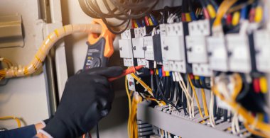 Elektrik mühendisi, elektrik kabinesi kontrolündeki voltaj ve elektrik akımını ölçen bir testçi ve röle koruma sistemindeki kabloları kontrol ediyor. Körfez kontrol birimi. Orta gerilim şalteri.