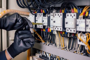 Elektrik mühendisi elektrik kabini kontrolündeki voltaj ve elektrik akımını ölçen bir testçi ve röle koruma sistemindeki kabloları kontrol ediyor. Körfez kontrol birimi. Orta gerilim şalteri.