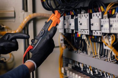 Elektrik mühendisi, elektrik kabinesi kontrolündeki voltaj ve elektrik akımını ölçen bir testçi ve röle koruma sistemindeki kabloları kontrol ediyor. Körfez kontrol birimi. Orta gerilim şalteri.