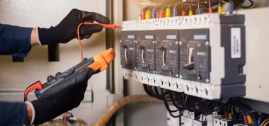 Elektrik mühendisi, elektrik kabinesi kontrolündeki voltaj ve elektrik akımını ölçen bir testçi ve röle koruma sistemindeki kabloları kontrol ediyor. Körfez kontrol birimi. Orta gerilim şalteri.