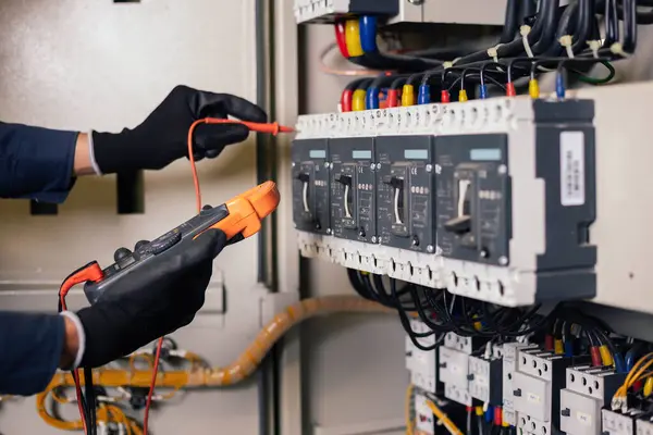 Elektrik mühendisi elektrik kabini kontrolündeki voltaj ve elektrik akımını ölçen bir testçi ve röle koruma sistemindeki kabloları kontrol ediyor. Körfez kontrol birimi. Orta gerilim şalteri.