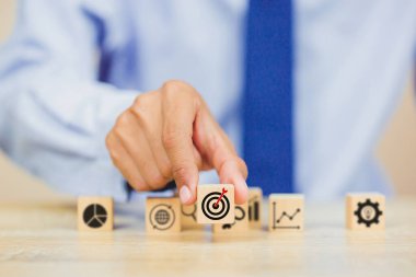 İş başarısı hedefleri kavramı. Yaratıcılık için ahşap küp bloğuna baskı yapan ve iş hedefi hedef kavramı oluşturan el ele tutuşan hedef tahtası, fikirler oluşturmak için engeller, hedef belirleme.