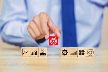 İş başarısı hedefleri kavramı. Yaratıcılık için ahşap küp bloğuna baskı yapan ve iş hedefi hedef kavramı oluşturan el ele tutuşan hedef tahtası, fikirler oluşturmak için engeller, hedef belirleme.