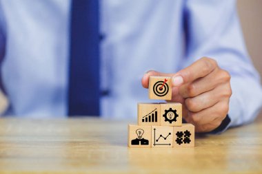 İş başarısı hedefleri kavramı. Yaratıcılık için ahşap küp bloğuna baskı yapan ve iş hedefi hedef kavramı oluşturan el ele tutuşan hedef tahtası, fikirler oluşturmak için engeller, hedef belirleme.