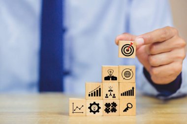 İş başarısı hedefleri kavramı. Yaratıcılık için ahşap küp bloğuna baskı yapan ve iş hedefi hedef kavramı oluşturan el ele tutuşan hedef tahtası, fikirler oluşturmak için engeller, hedef belirleme.