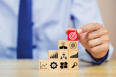 İş başarısı hedefleri kavramı. Yaratıcılık için ahşap küp bloğuna baskı yapan ve iş hedefi hedef kavramı oluşturan el ele tutuşan hedef tahtası, fikirler oluşturmak için engeller, hedef belirleme.