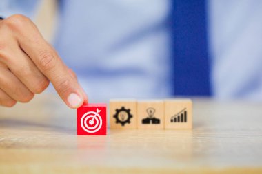 İş başarısı hedefleri kavramı. Yaratıcılık için ahşap küp bloğuna baskı yapan ve iş hedefi hedef kavramı oluşturan el ele tutuşan hedef tahtası, fikirler oluşturmak için engeller, hedef belirleme.