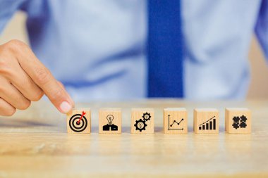 İş başarısı hedefleri kavramı. Yaratıcılık için ahşap küp bloğuna baskı yapan ve iş hedefi hedef kavramı oluşturan el ele tutuşan hedef tahtası, fikirler oluşturmak için engeller, hedef belirleme.