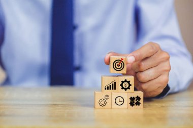 İş başarısı hedefleri kavramı. Yaratıcılık için ahşap küp bloğuna baskı yapan ve iş hedefi hedef kavramı oluşturan el ele tutuşan hedef tahtası, fikirler oluşturmak için engeller, hedef belirleme.