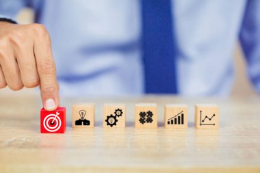 İş başarısı hedefleri kavramı. Yaratıcılık için ahşap küp bloğuna baskı yapan ve iş hedefi hedef kavramı oluşturan el ele tutuşan hedef tahtası, fikirler oluşturmak için engeller, hedef belirleme.