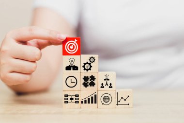 İş başarısı hedefleri kavramı. Yaratıcılık için ahşap küp bloğuna baskı yapan ve iş hedefi hedef kavramı oluşturan el ele tutuşan hedef tahtası, fikirler oluşturmak için engeller, hedef belirleme.