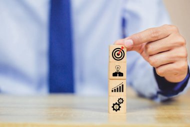 İş başarısı hedefleri kavramı. Yaratıcılık için ahşap küp bloğuna baskı yapan ve iş hedefi hedef kavramı oluşturan el ele tutuşan hedef tahtası, fikirler oluşturmak için engeller, hedef belirleme.